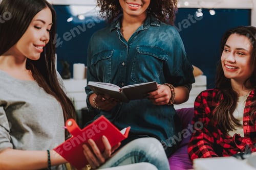 Preview: Side View Of Joyful International Female Making Entries In Their Diaries. Discussion Concept