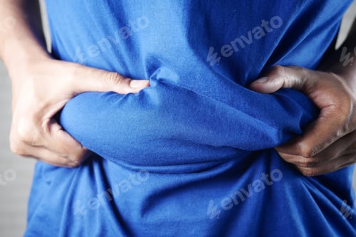 Preview: man's hand holding excessive belly fat, overweight concept