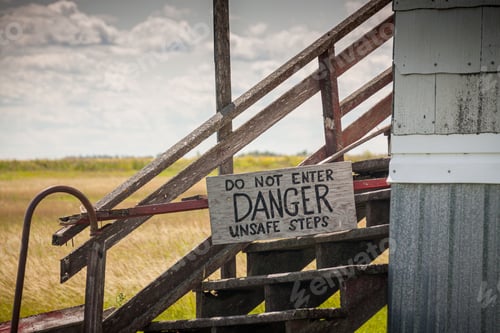 Preview: Field with old rickety stairs next to a house with a danger sign