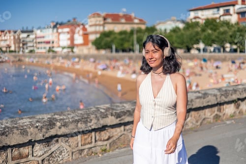 Preview: copyspace Young woman enjoying music walking near the beach in summer