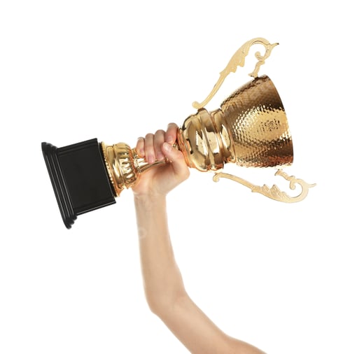 Preview: Young woman holding gold trophy cup on white background, closeup