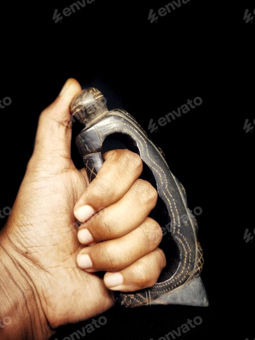 Preview: Vertical closeup of an ancient wooden knuckle on hand against a black background