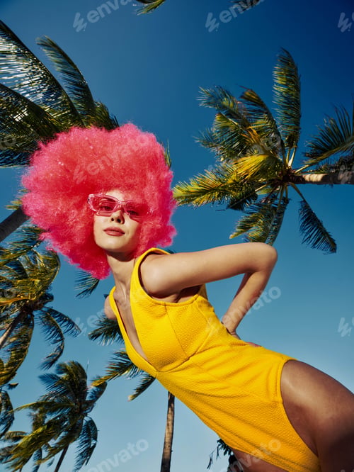 Preview: Woman, yellow swimsuit, pink wig, palm trees a woman in a vibrant yellow swimsuit and playful pink