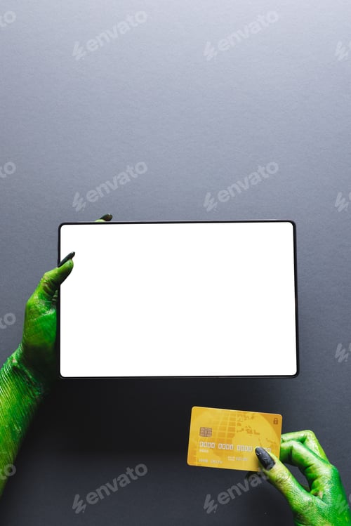 Preview: Vertical image of green monster hands with credit card and tablet with copy space on grey background
