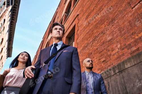 Preview: Businessmen and women walking outdoors, low angle view