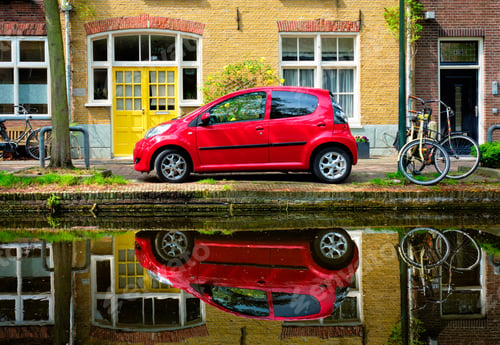 Preview: Red car on canal embankment in street of Delft. Delft, Netherlands
