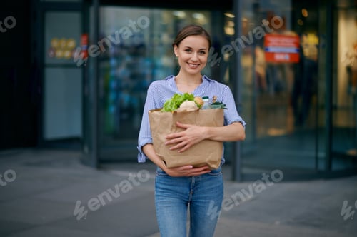 Preview: Woman with food in bag on supermarket car parking