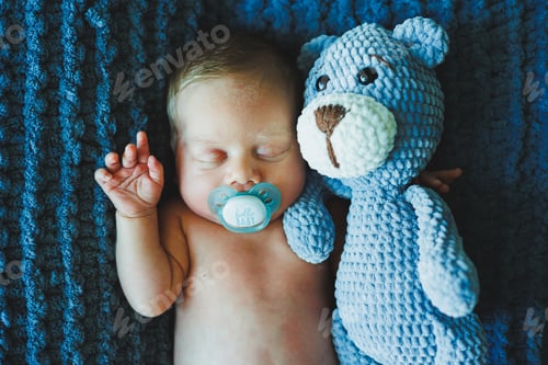 Preview: A newborn baby sleeps with a knitted teddy bear. Children's knitted toys. Baby sleep