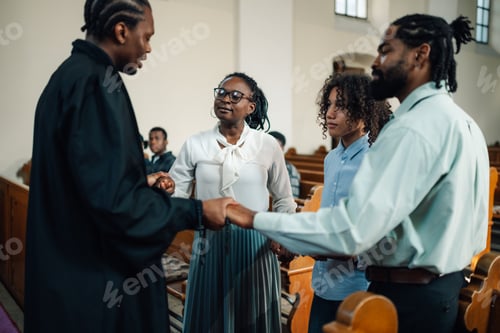 Preview: Priest holding hands with family praying in church