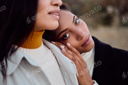 Preview: Beautiful African American girl thoughtfully looking in camera leaning head on friend shoulder