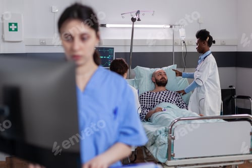 Preview: Black doctor checking hospitalized sick man monitoring sickness symptom