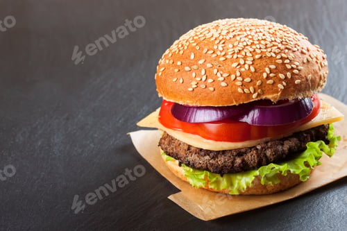 Preview: Homemade cheeseburger on black slate surface.