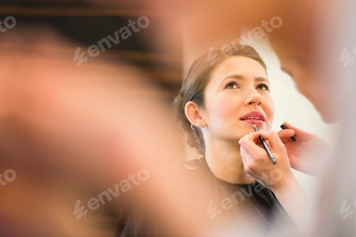 Preview: Female friend applying lip liner to brides lips