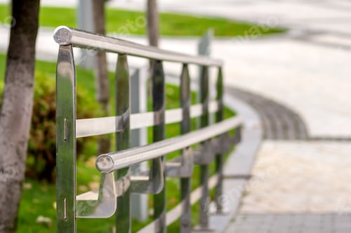 Preview: Metal fence construction made of shiny wet stainless pipes along road highway turn