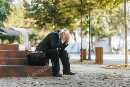 Preview: Depressed senior businessman overwhelmed with job loss sitting on steps