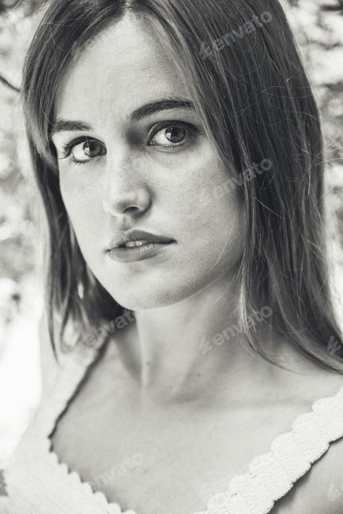Preview: Greyscale shot of an attractive girl with long hair staring at the camera in the park