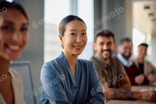 Preview: Happy Korean businesswoman during a meeting in the office looking at camera.