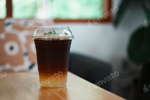 Preview: Black coffee with ice in plastic glass on the table, close up