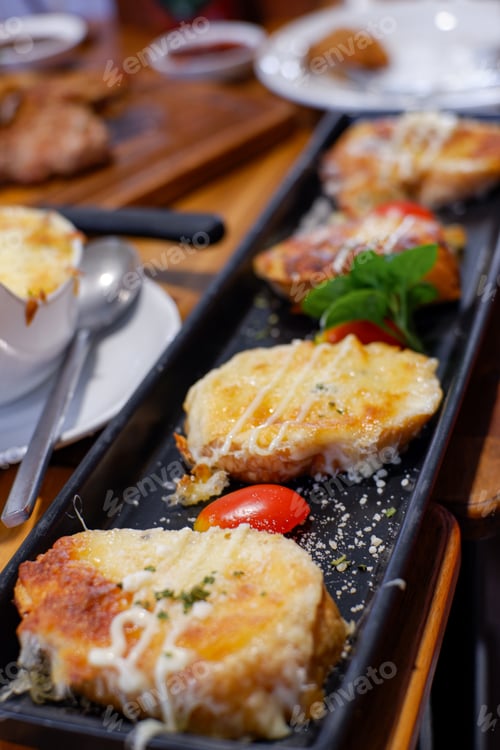Preview: Slices of toasted bread with garlic, cheese and herbs on wooden table. Toned with color filter and s