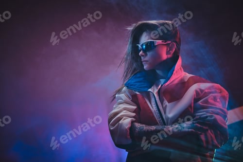 Preview: Inked attractive female posing in a neon vivid lights of a studio surrounded by smoke