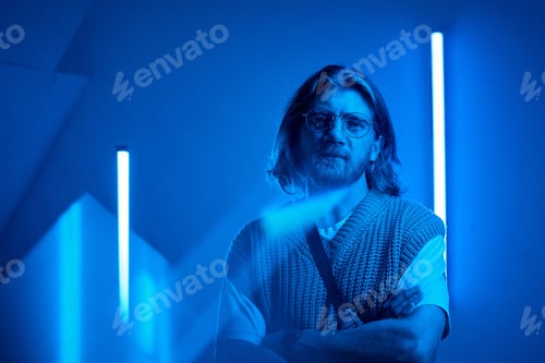 Preview: Portrait of Man in Neon Blue Light Setting with Folded Arms