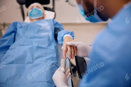 Preview: Close up of doctor putting pulse oximeter on patient's finger before surgery in the hospital.
