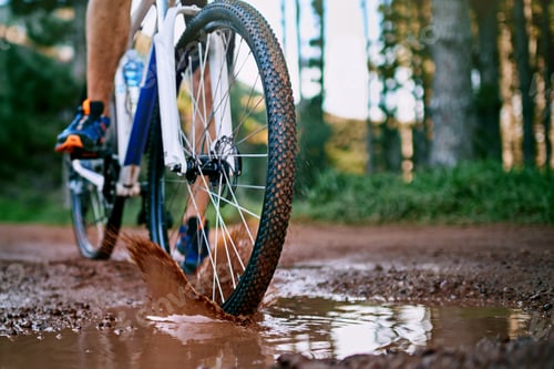 Preview: Cropped shot of a male cyclist riding along a muddy mountain bike trail