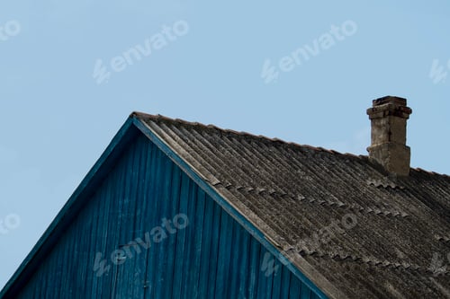 Preview: The roof with the pipe on the old house. Sunny summer day. Side view.