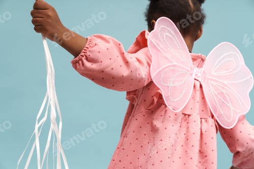 Preview: African girl wearing pink dress with angel wings holding ropes