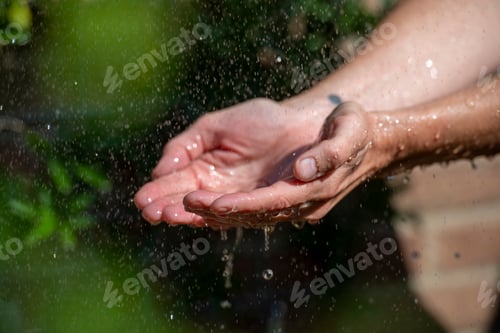 Preview: Hands catching splashing water droplets.