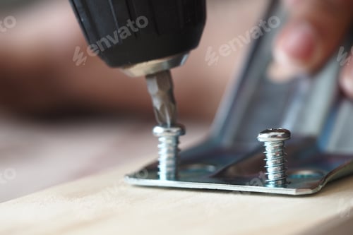 Preview: Close-up of a person using a drill on metal brackets
