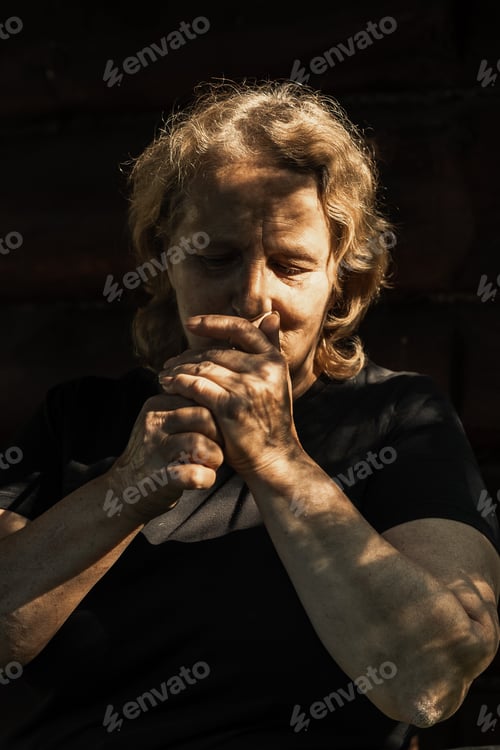 Preview: Portrait of elderly woman with cigarette close-up on natural background. Sunset light on face of sen