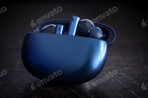 Preview: Closeup shot of blue wireless earbuds in a box container on a dark gray surface.