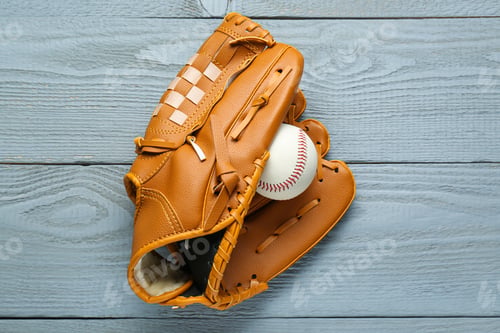 Preview: Leather baseball glove with ball on grey wooden table, top view