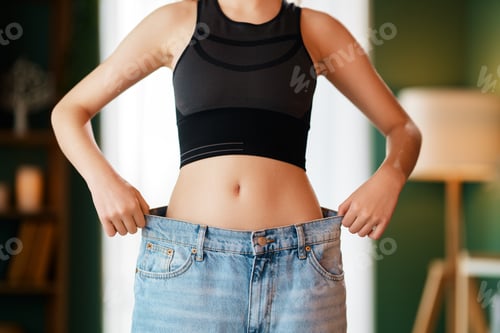 Preview: A young woman is trying on big jeans