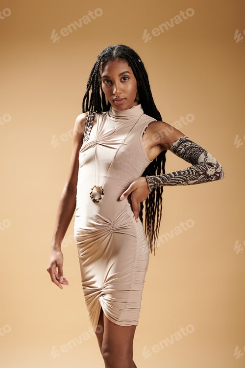 Preview: Stylish young woman with unique attire poses elegantly against a warm background