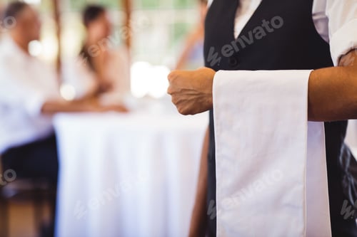 Preview: Mid section of waitress standing with napkin in restaurant