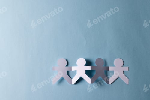 Preview: Close up of four paper cut out people figures holding hands with copy space on blue background
