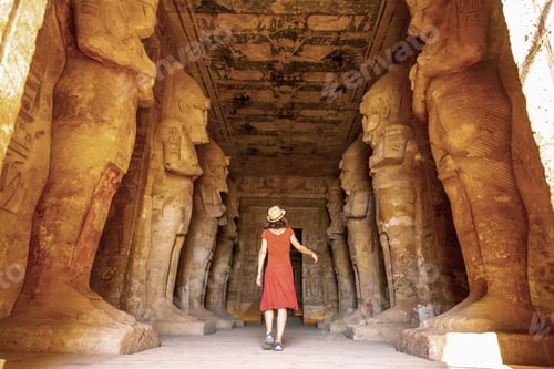 Preview: A young woman in a red dress at the Abu Simbel Temple next to the sculptures