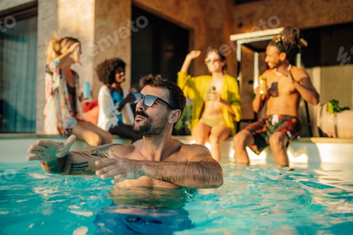 Preview: Man relaxing in swimming pool while friends are having fun