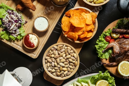 Preview: top view beer snacks smoked quail pigtail cheese pistachios lemon chips on the table
