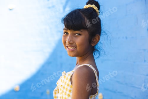 Visualização: Garota birracial sorri brilhantemente contra um fundo azul