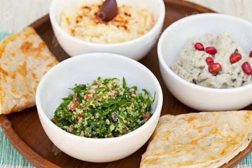 Preview: Assortment of dips: hummus, chickpea dip, tabbouleh salad, baba ganoush and flat bread, pita on a