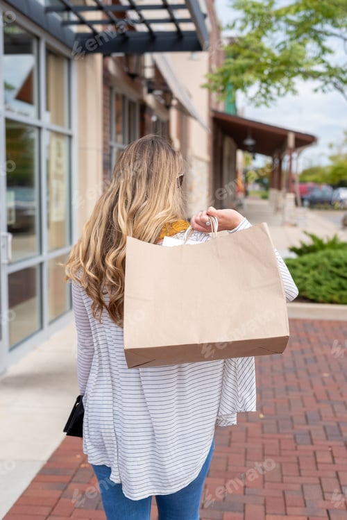 Preview: Back view of young woman carrying shopping bags