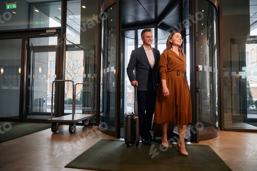 Preview: Adult caucasian couple with suitcases entering to hotel lobby at sunny day