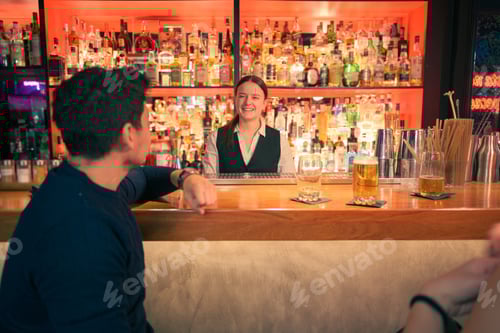 Preview: Smiling bartender serving drinks at cozy pub in the evening
