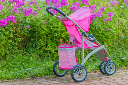 Preview: Baby pink stroller in a city park. The child lost the pram. Toy carriage for dolls in a public park
