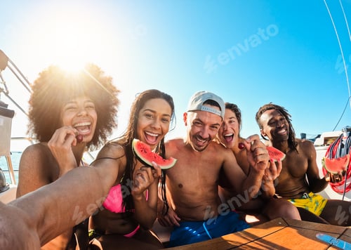Preview: Happy multiracial friends eating watermelon while doing selfie during sea tour with sailing boat