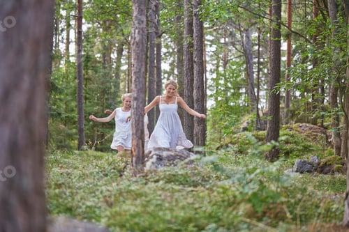 Preview: Two girls in white dresses running playfully through a sunlit forest