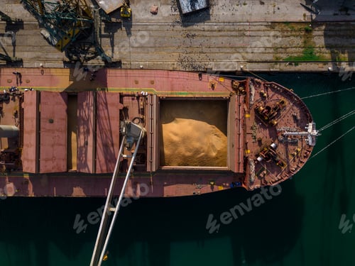 Preview: cargo ship or bulk carrier loaded to the brim with grain is preparing for departure, working sailors